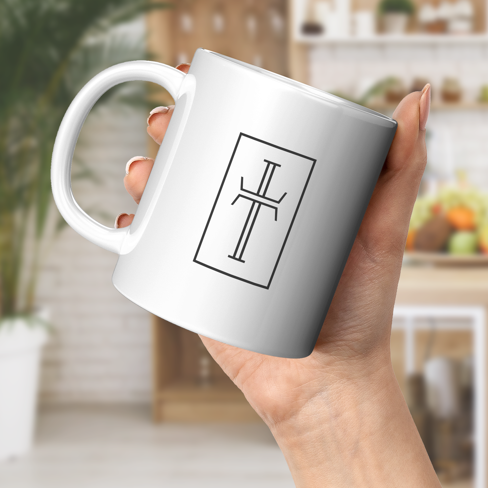 White mug with a cross logo held by a female hand in a blurred indoor setting.