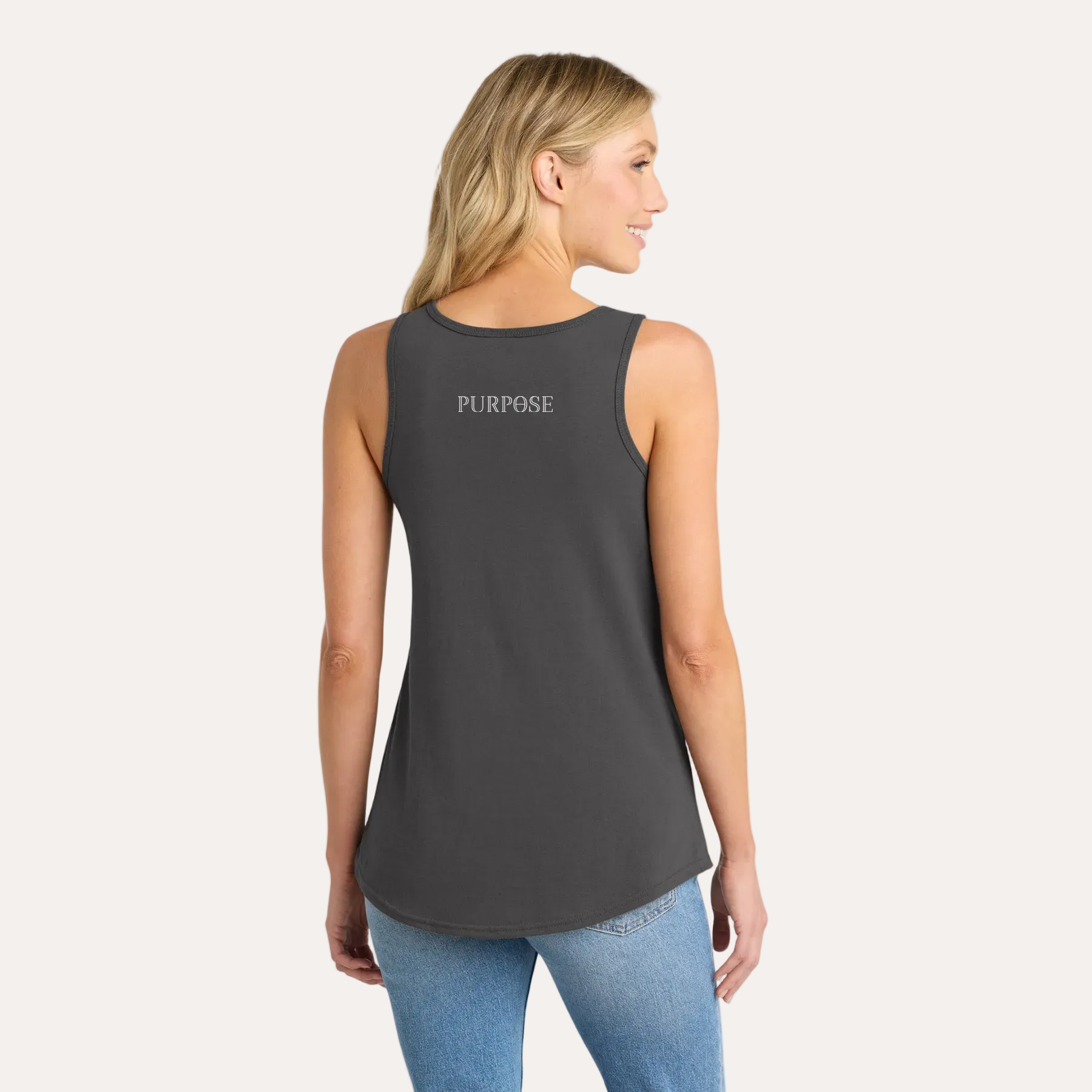 Woman wearing a dark gray tank top and blue jeans on a white background