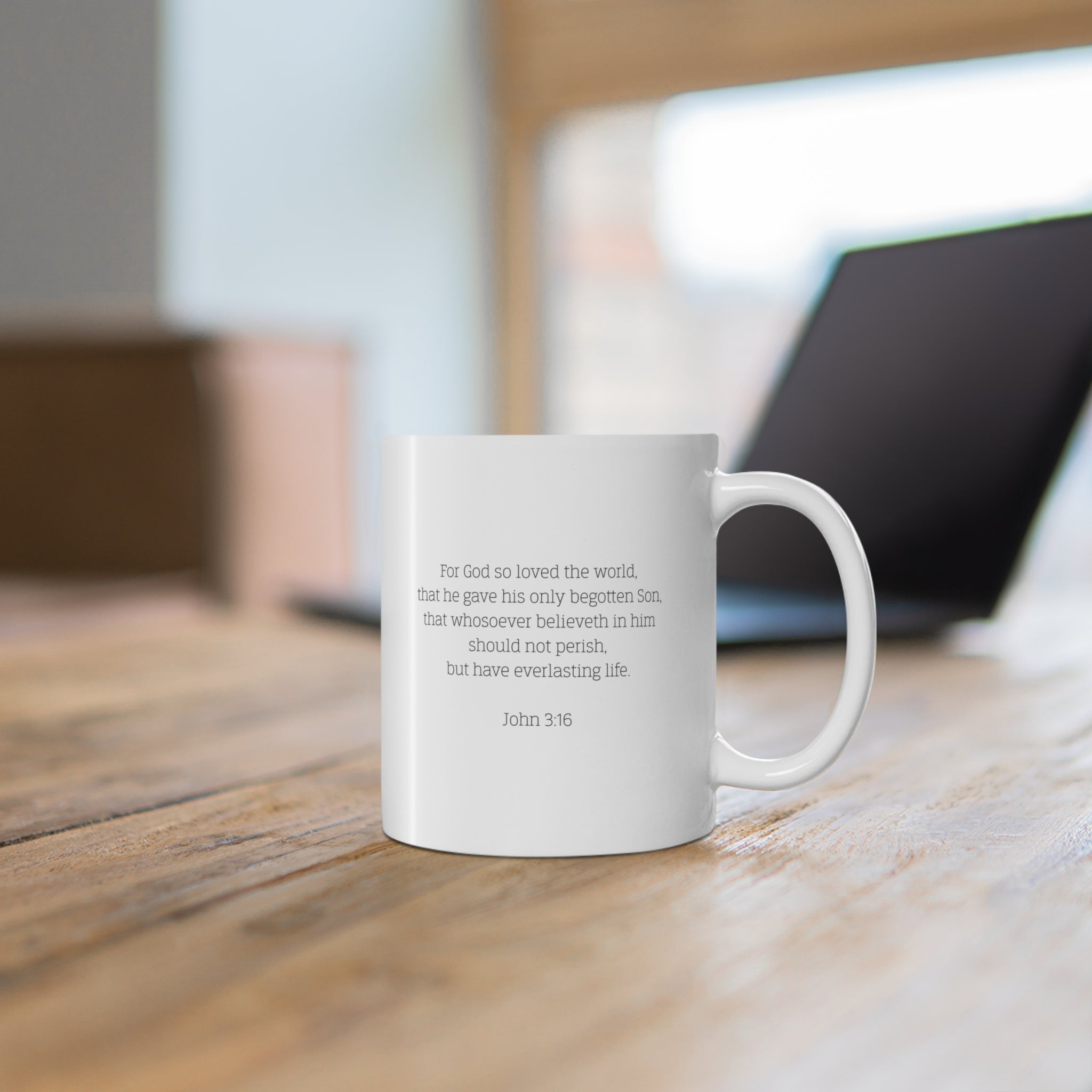 White mug with Biblical verse John 3:16 on a wooden desk