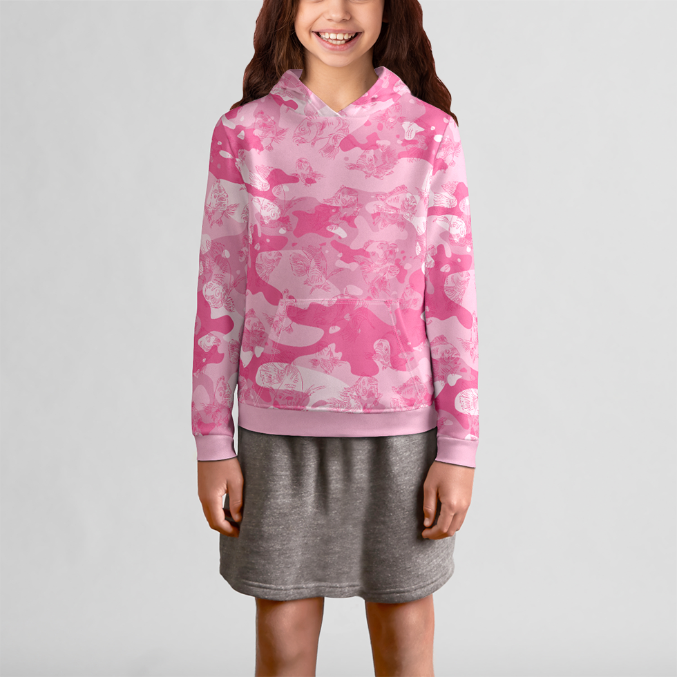 The front view of a female youth model in a gray skirt is wearing a pink-camo hoodie with a dark pink, all-over print line drawing of swimming carp. The hoodie has ribbed banding along the cuffs and bottom, and a kangaroo pocket.