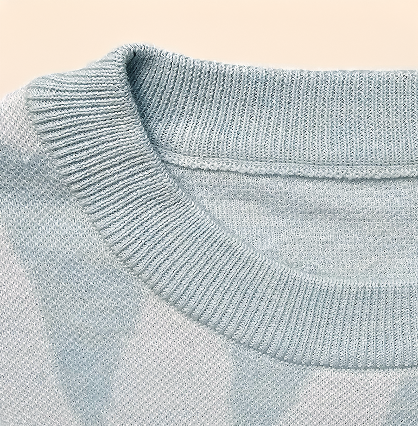 Close-up of a light blue ribbed sweater collar on a beige background