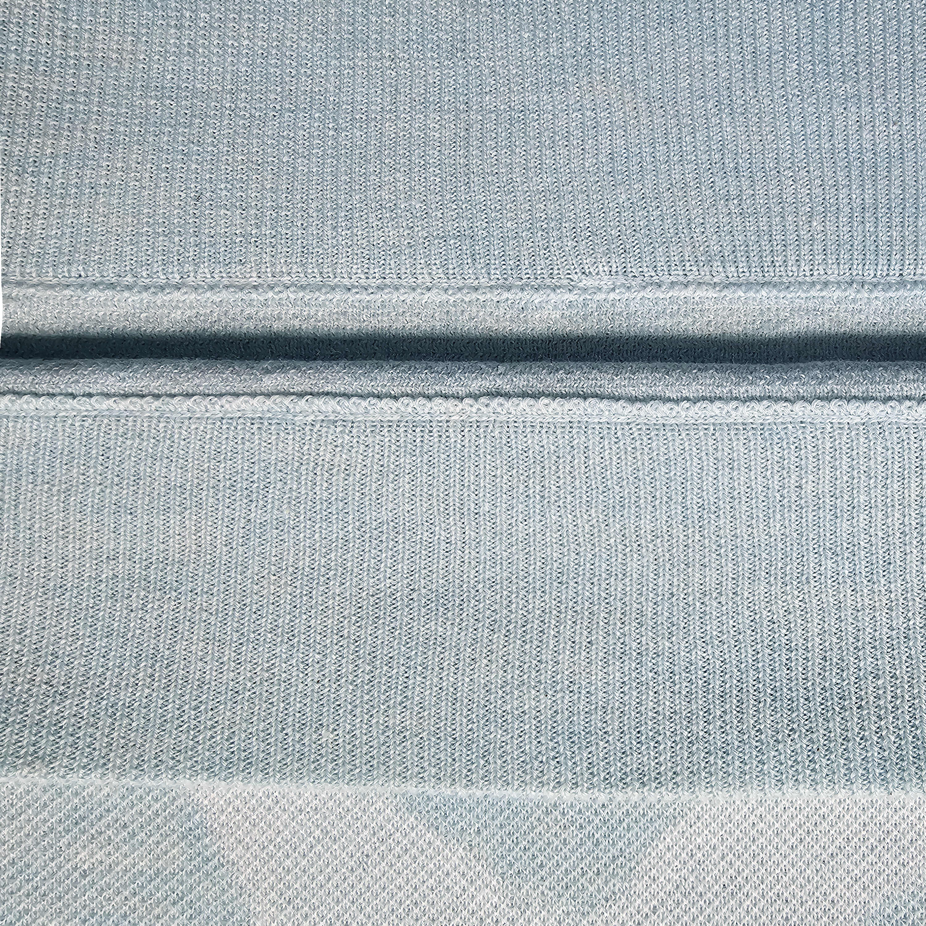Close-up of light blue knitted sweater with a subtle white pattern of doves and leaves.