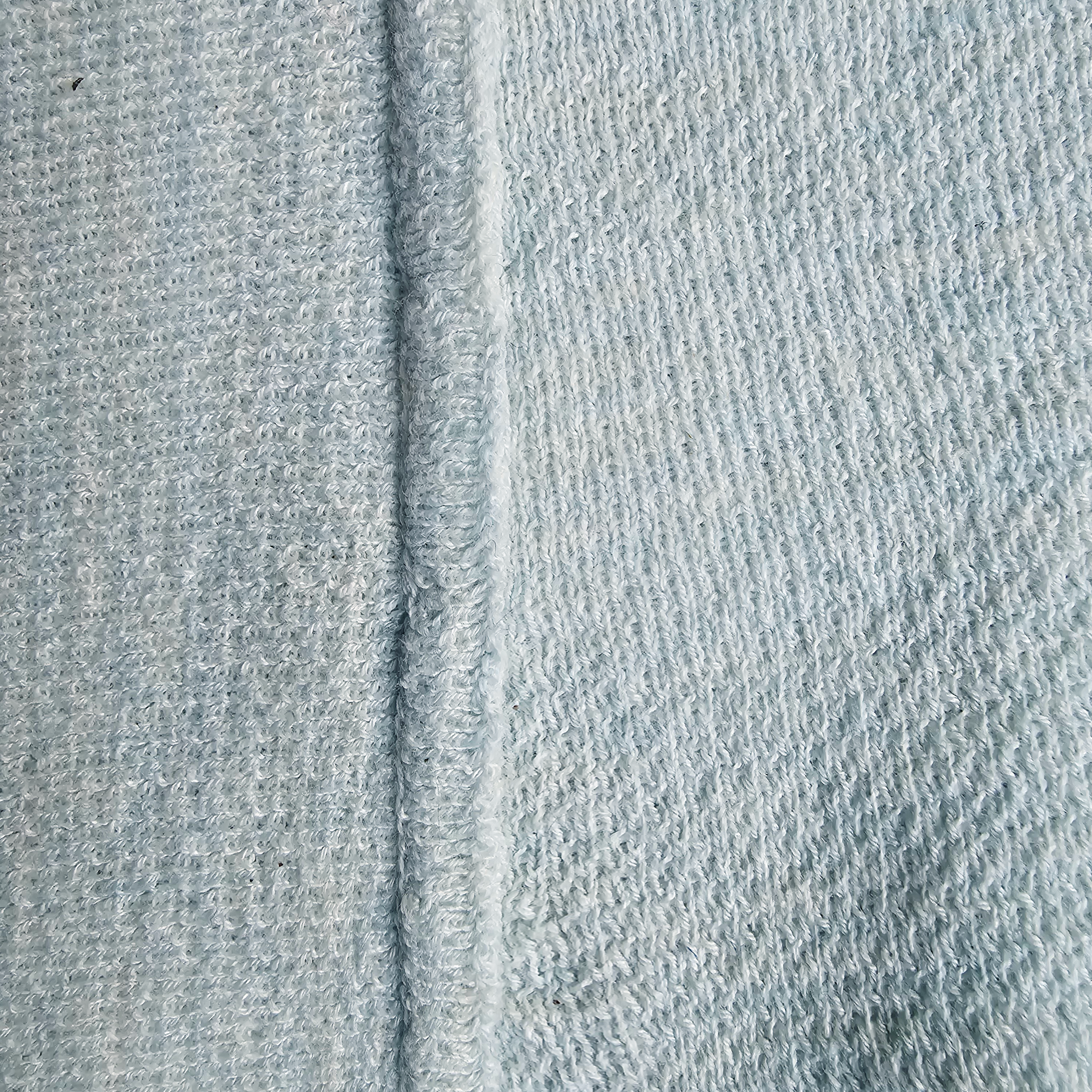 Close-up of knitted light blue sweater with an inner seam.