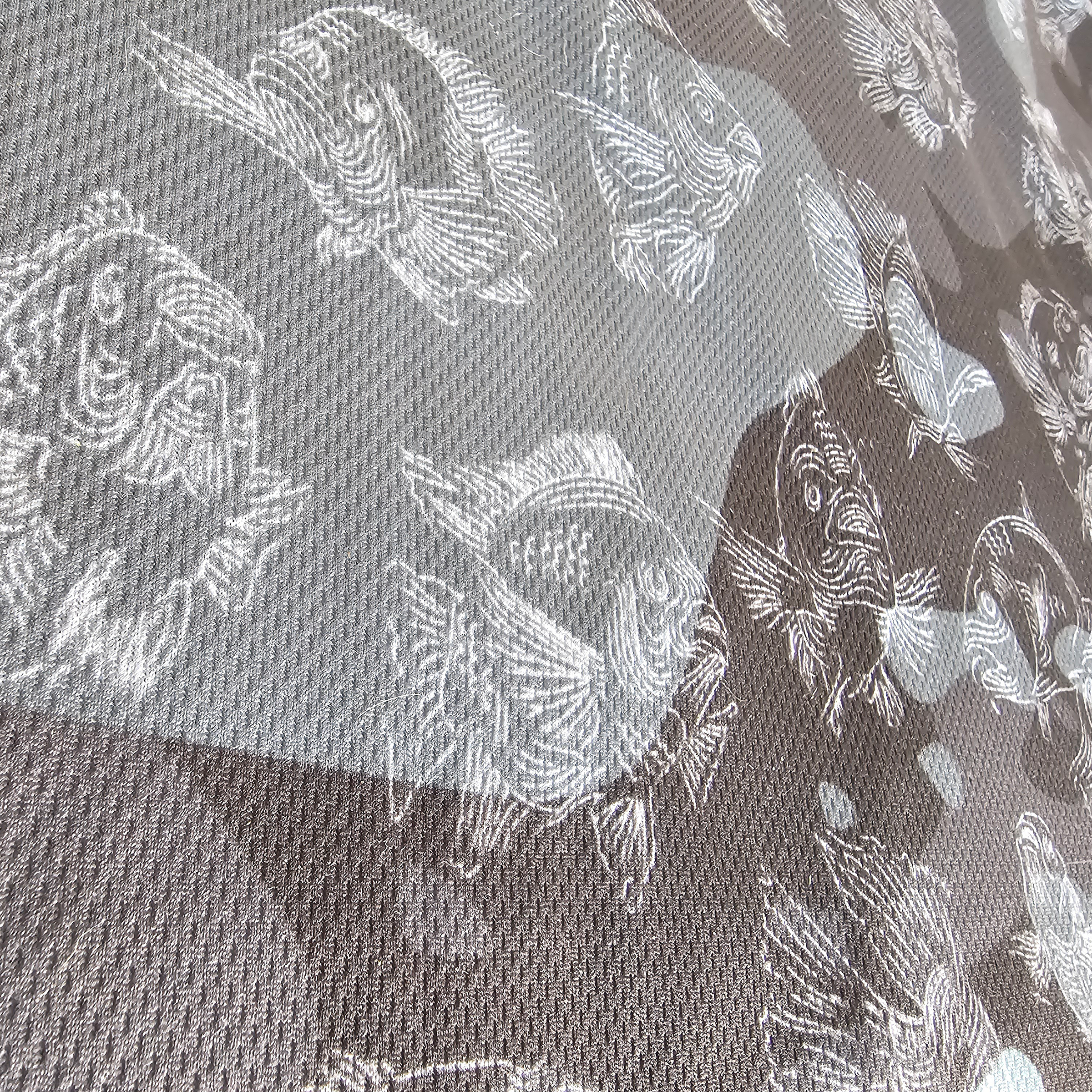 Close-up of a gray, blue, and black fabric with a white carp pattern, showing the texture and design details.