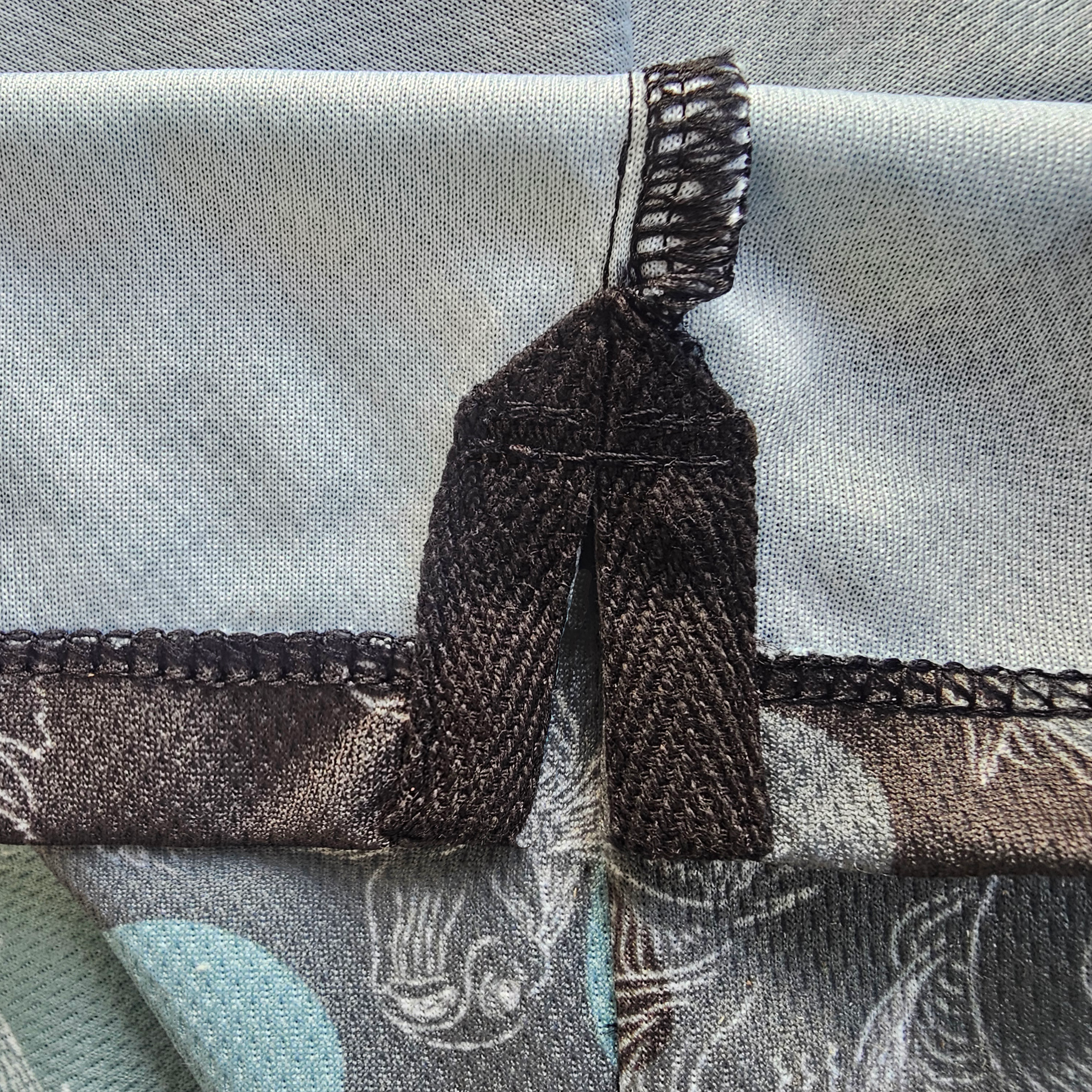 Close-up of a fabric garment detail showing a black woven ribbon sewn onto the reverse side of the bottom shirt seam placket.