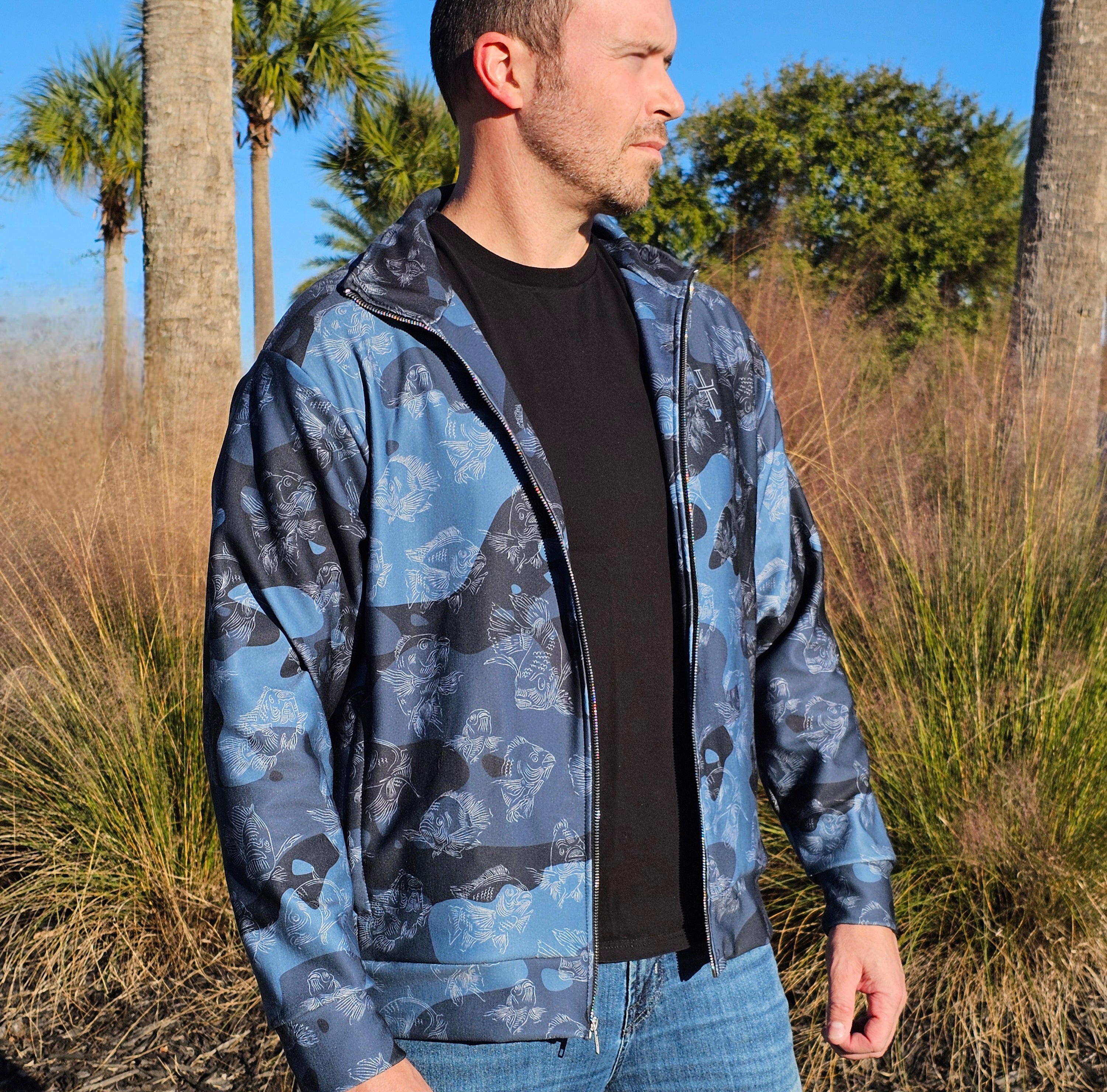 Man wearing a blue camouflage jacket with palm trees in the background
