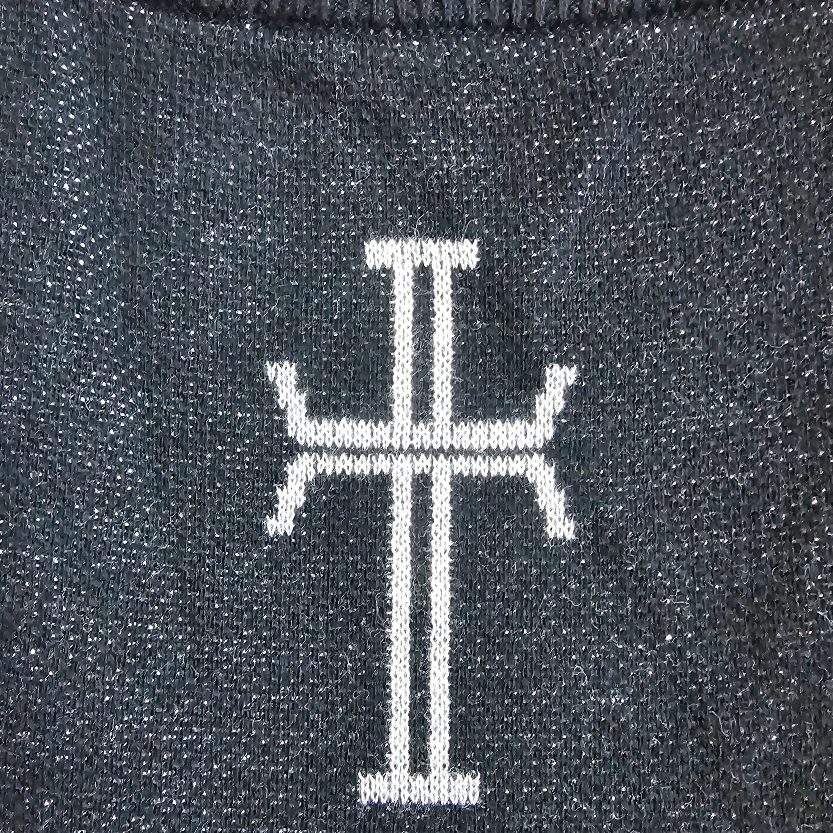 Close-up of a dark charcoal gray knit sweater featuring a white stylized cross on the chest.