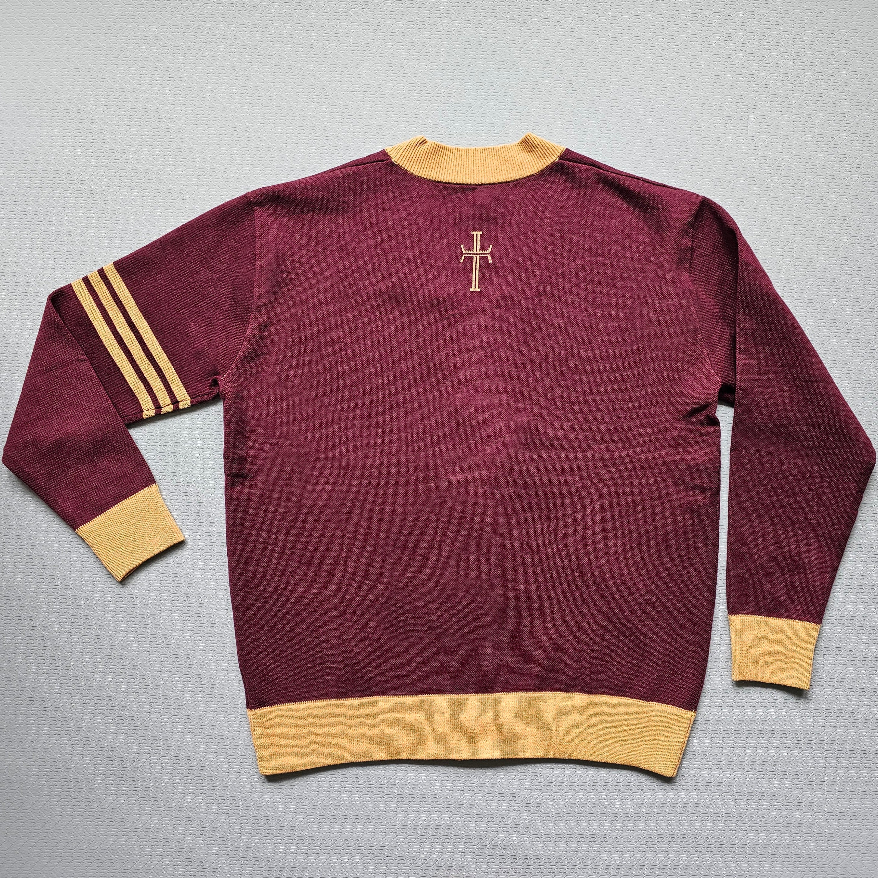 Maroon sweater with gold accents on a gray background