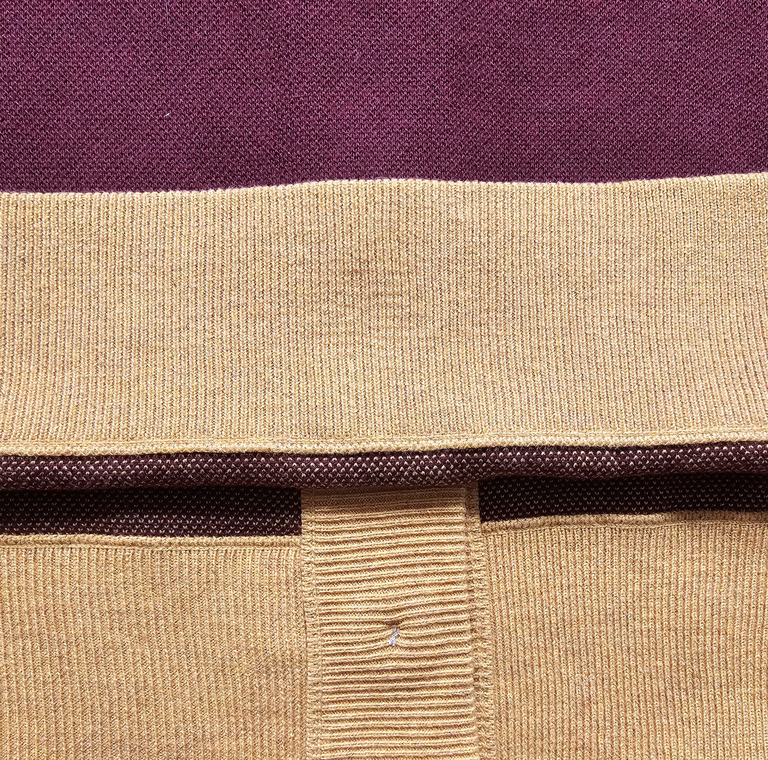 Close-up of a maroon and mustard-colored knitted fabric with a visible seam.