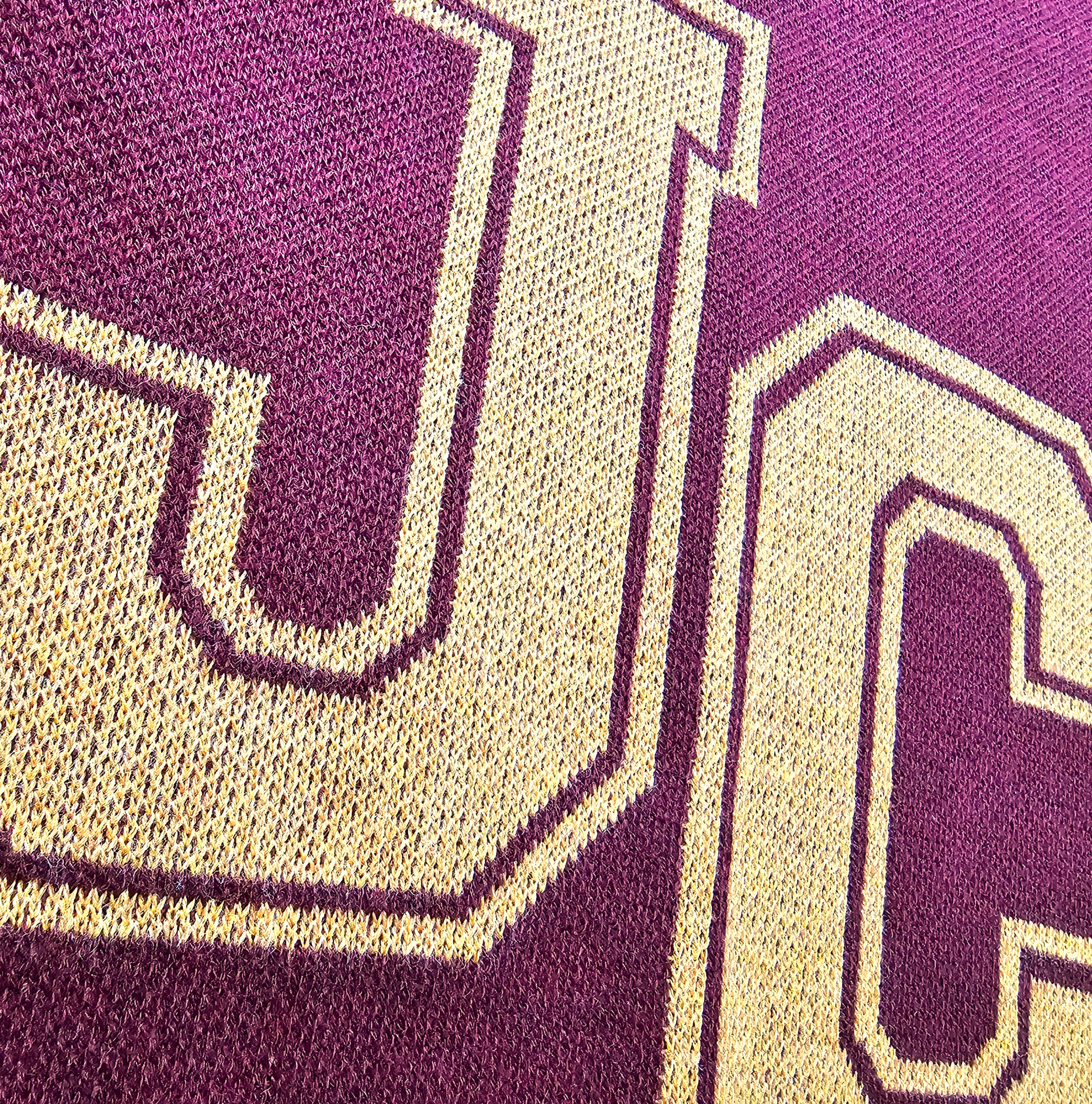 Close-up of a textured knitted fabric with a prominent 'JC' logo.