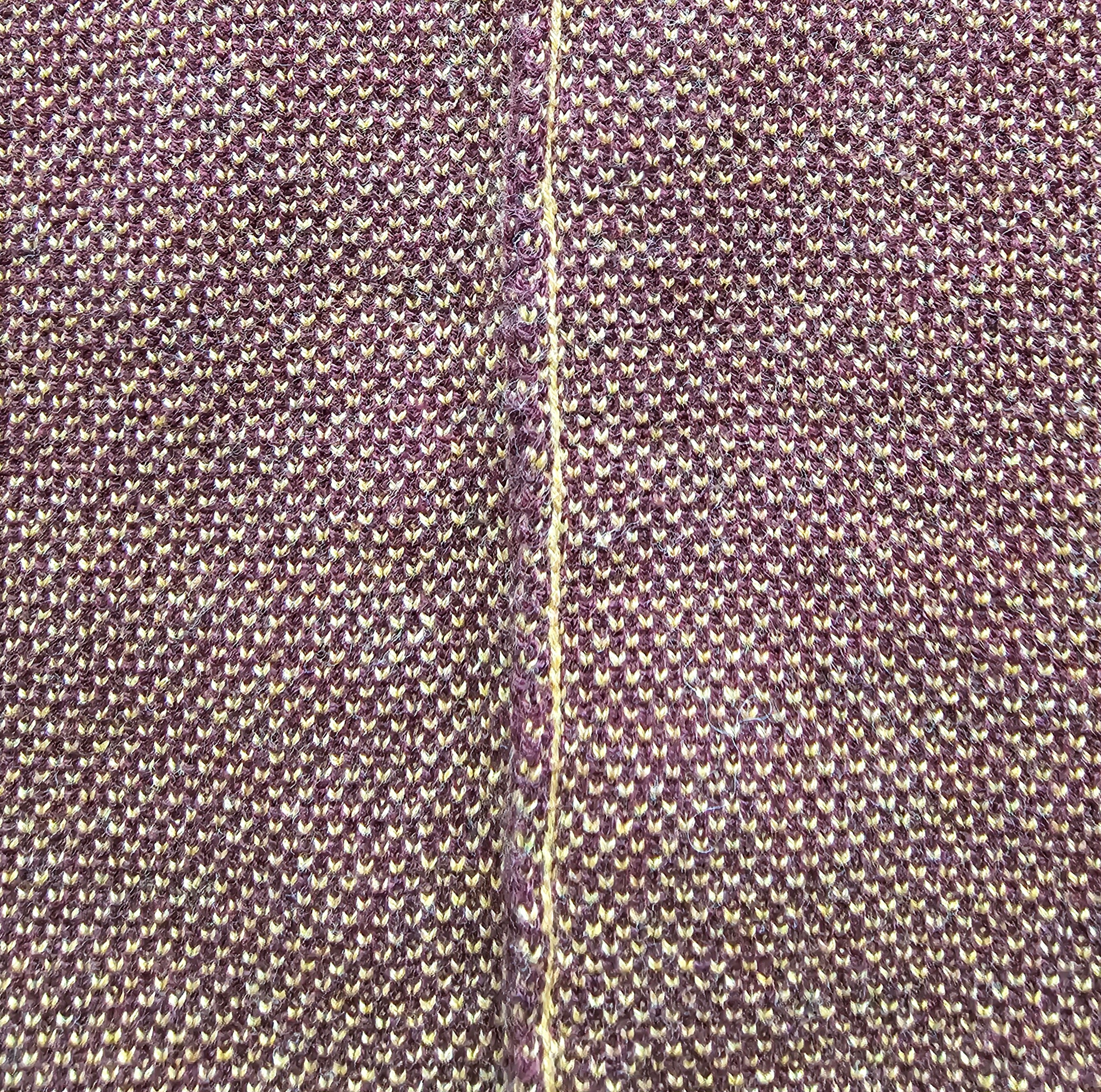 Close-up of textured maroon knit fabric with a visible knitted seam.