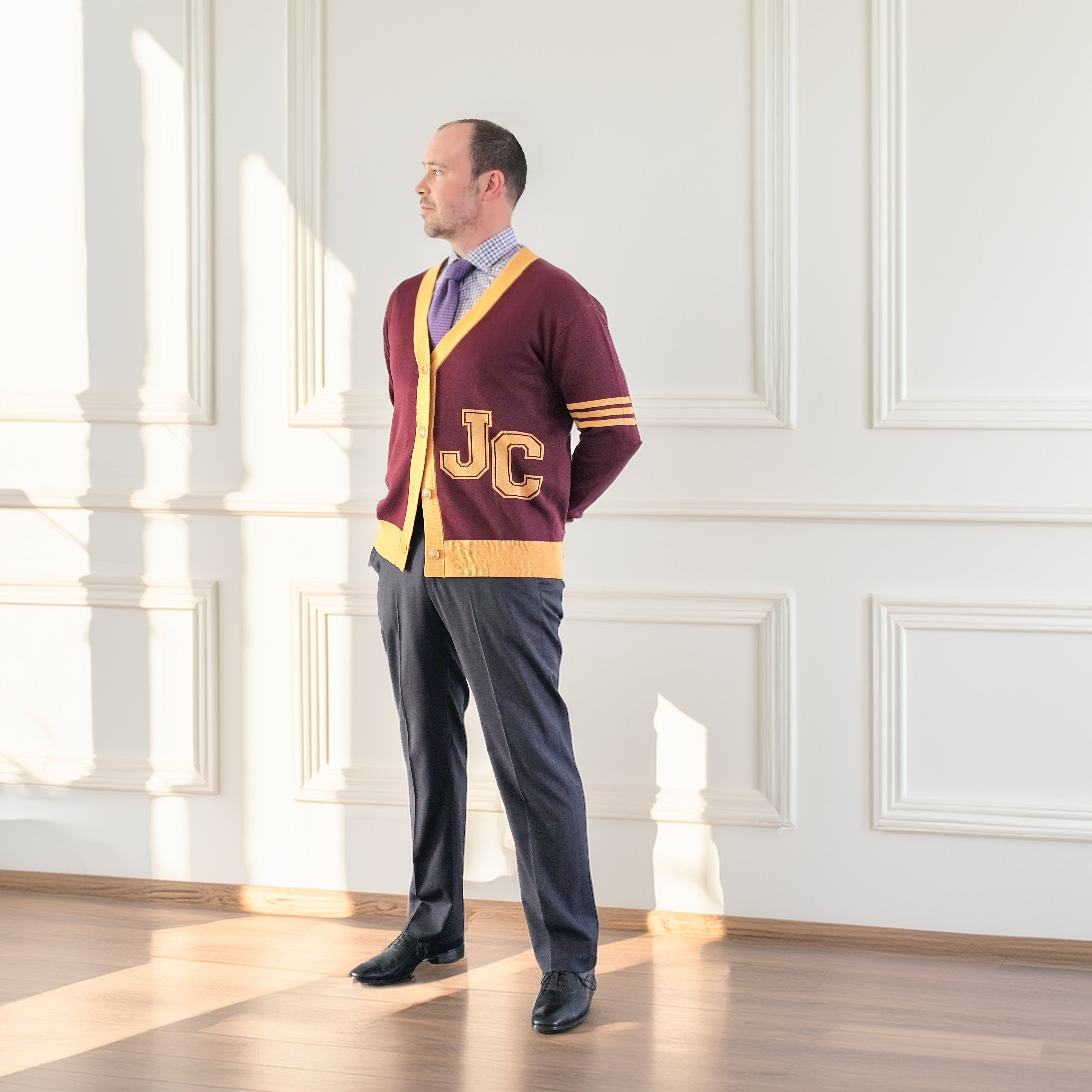 Man wearing a maroon sweater with 'JC' letters in a bright room