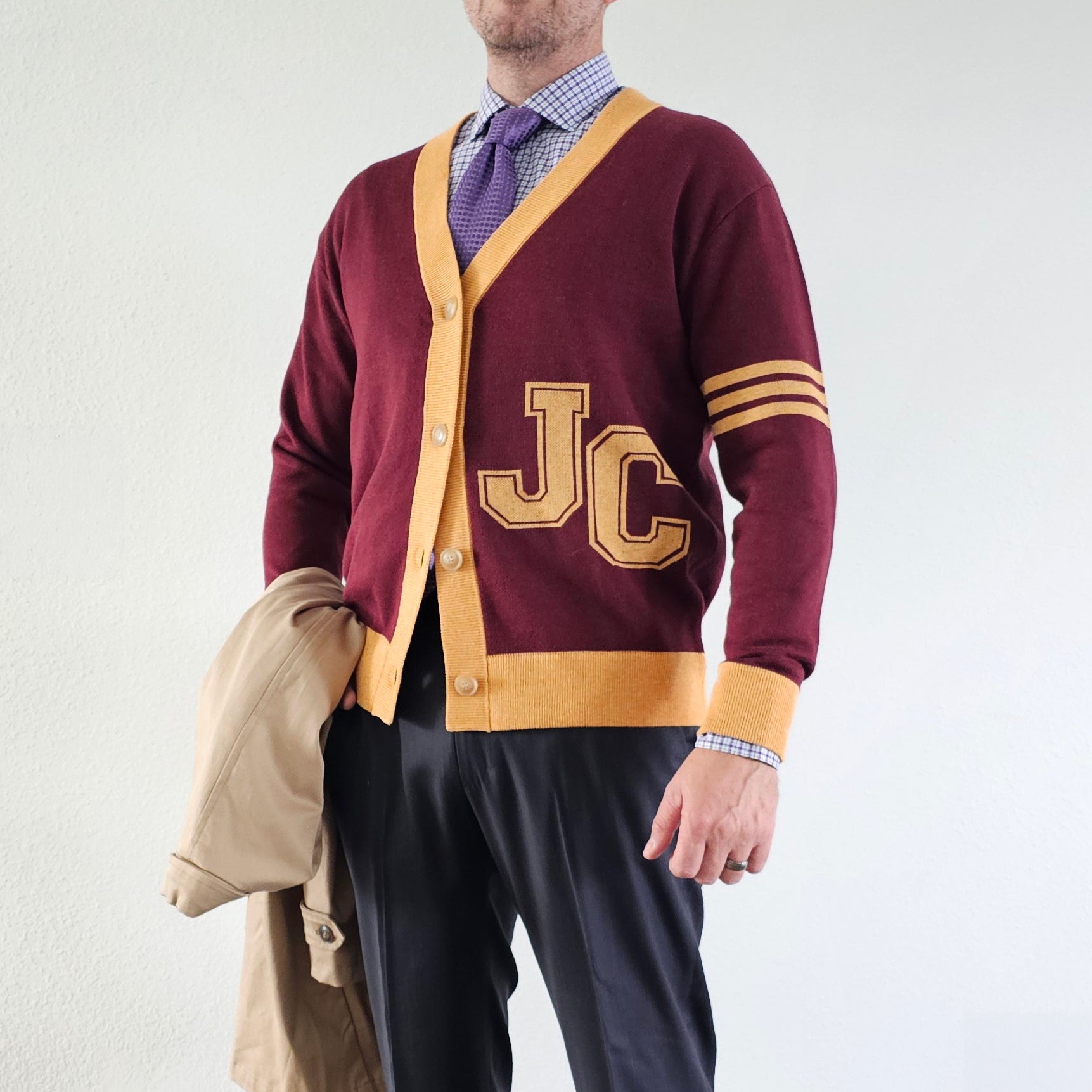 Person wearing a maroon and gold cardigan with 'JC' lettering on a white background