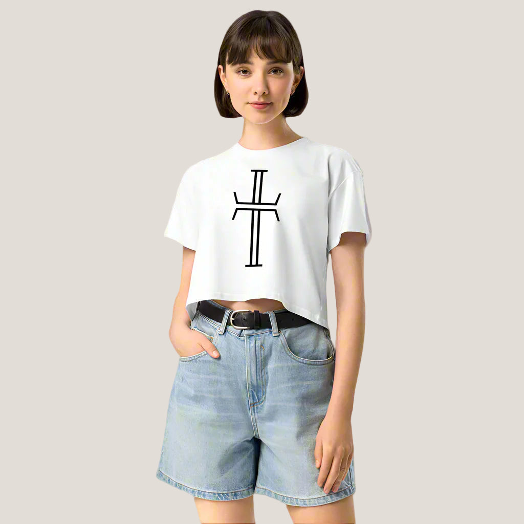 Woman in cropped white t-shirt with a stylized crucifix and jean shorts
