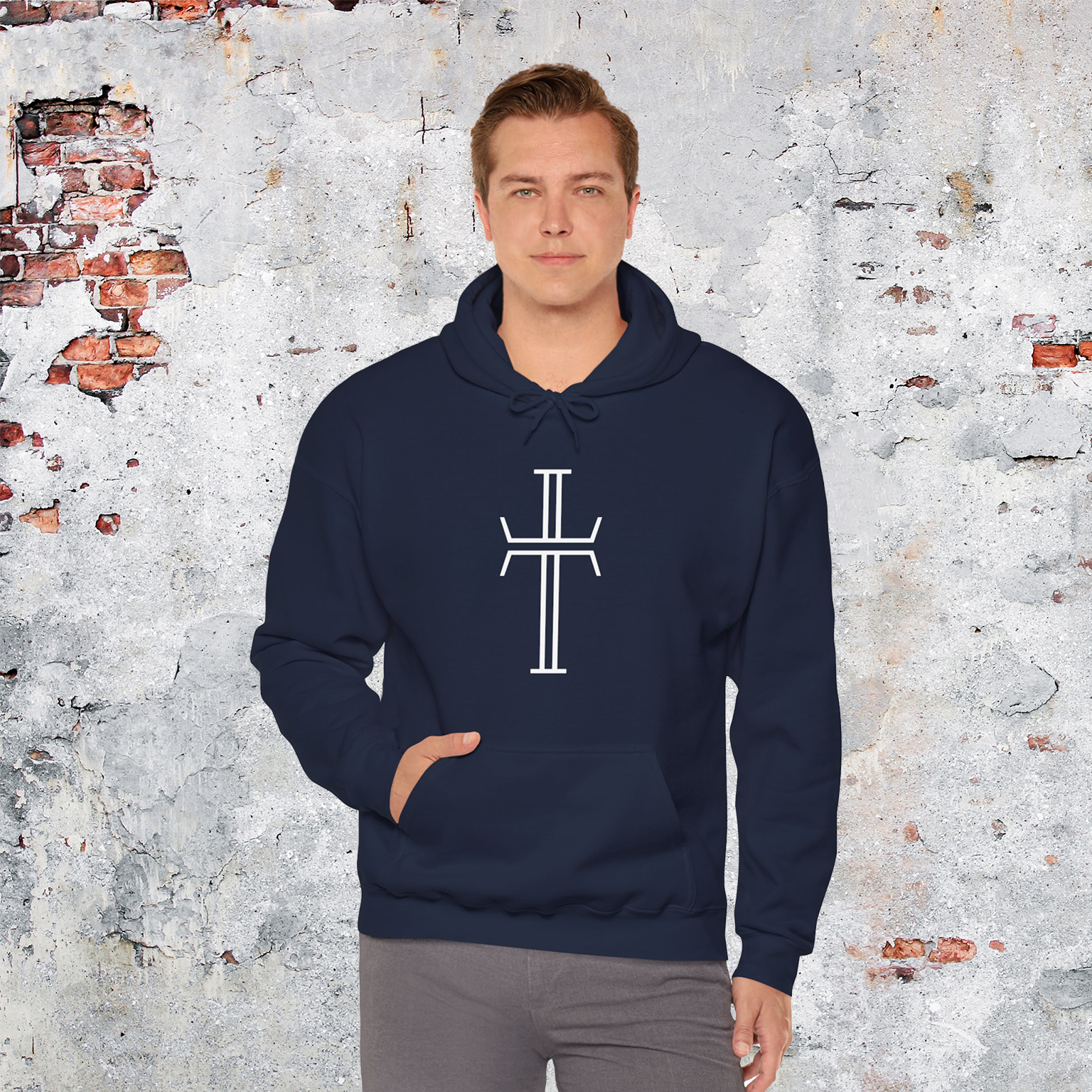 A tall, handsome man in gray denim wears a navy hoodie that displays the large white Purpose cross logo on the front.