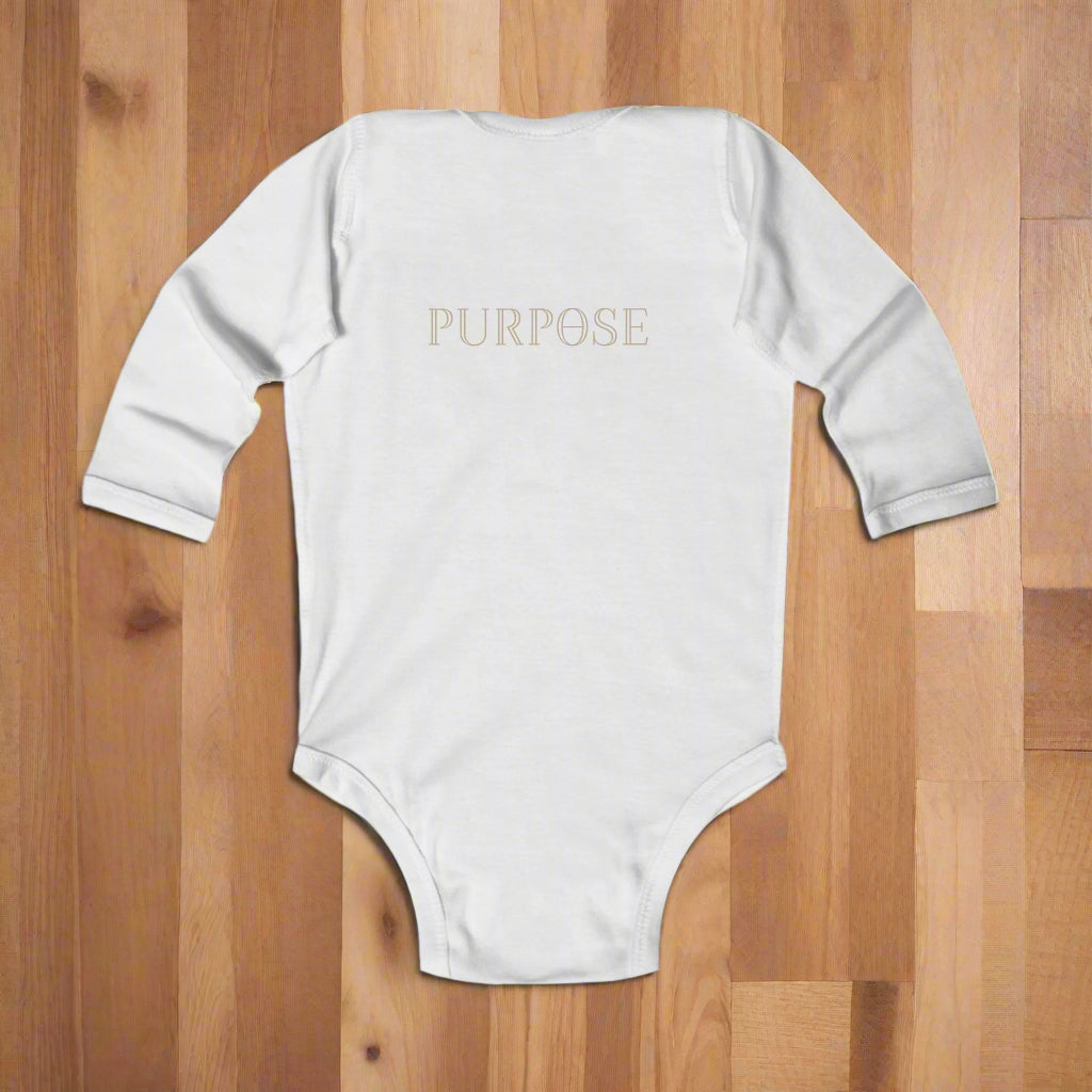 White baby onesie with 'PURPOSE' printed on the back against a wood floor background