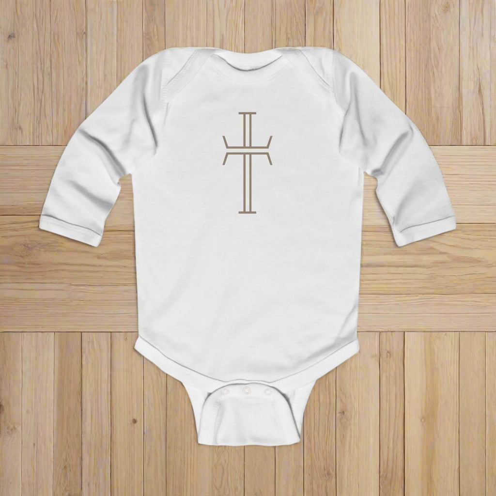 White baby onesie with a cross design on a wood floor background