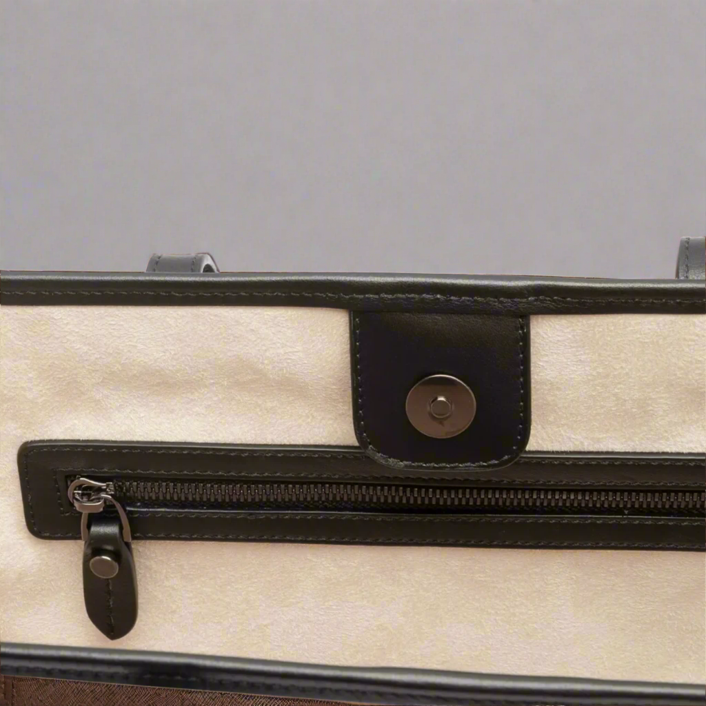 Close-up of a tote bag with a black handle and zipper on a gray background