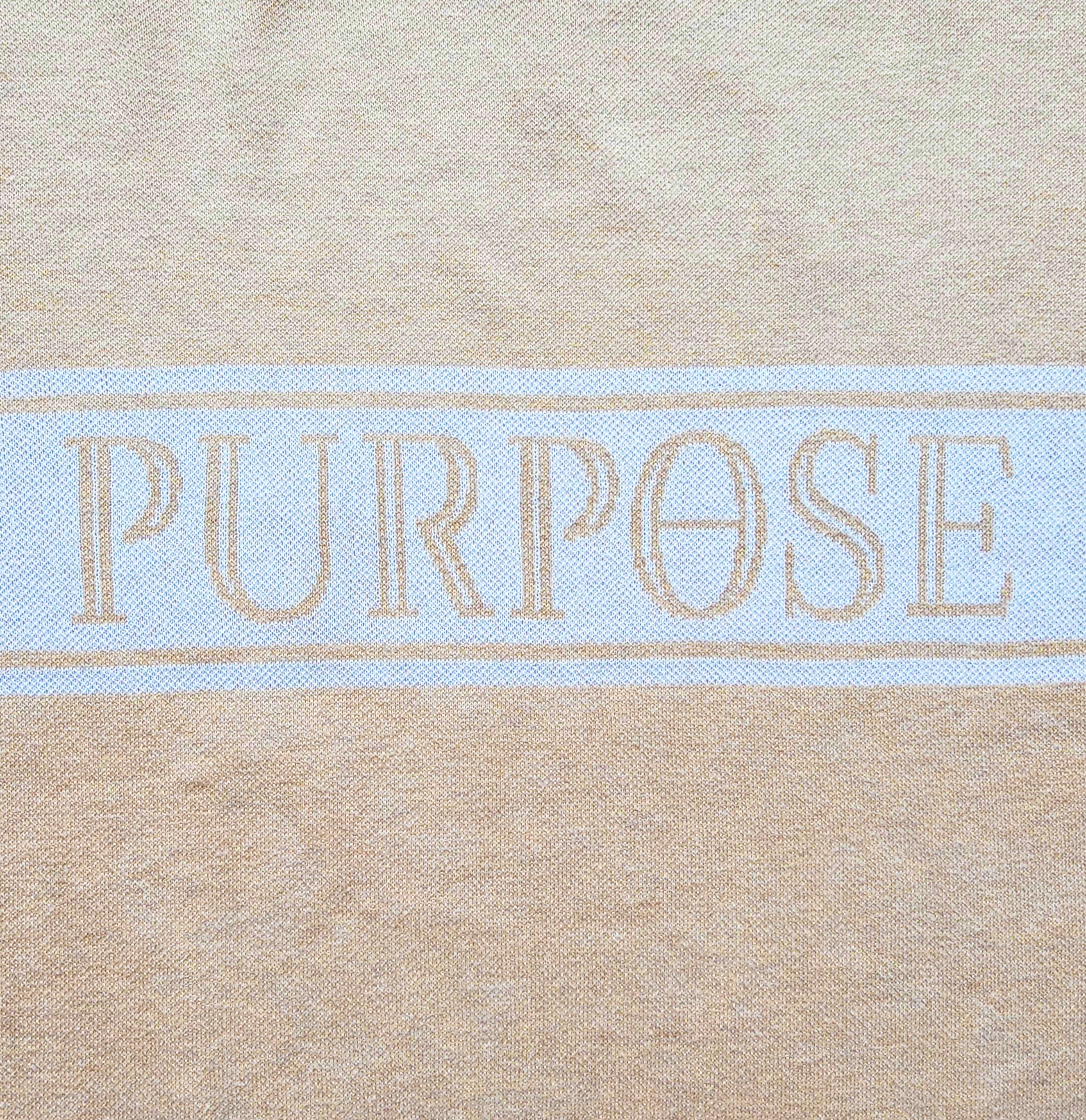 Close-up of the capitalized "Purpose" word knitted on the center stripe of the front sweater chest.