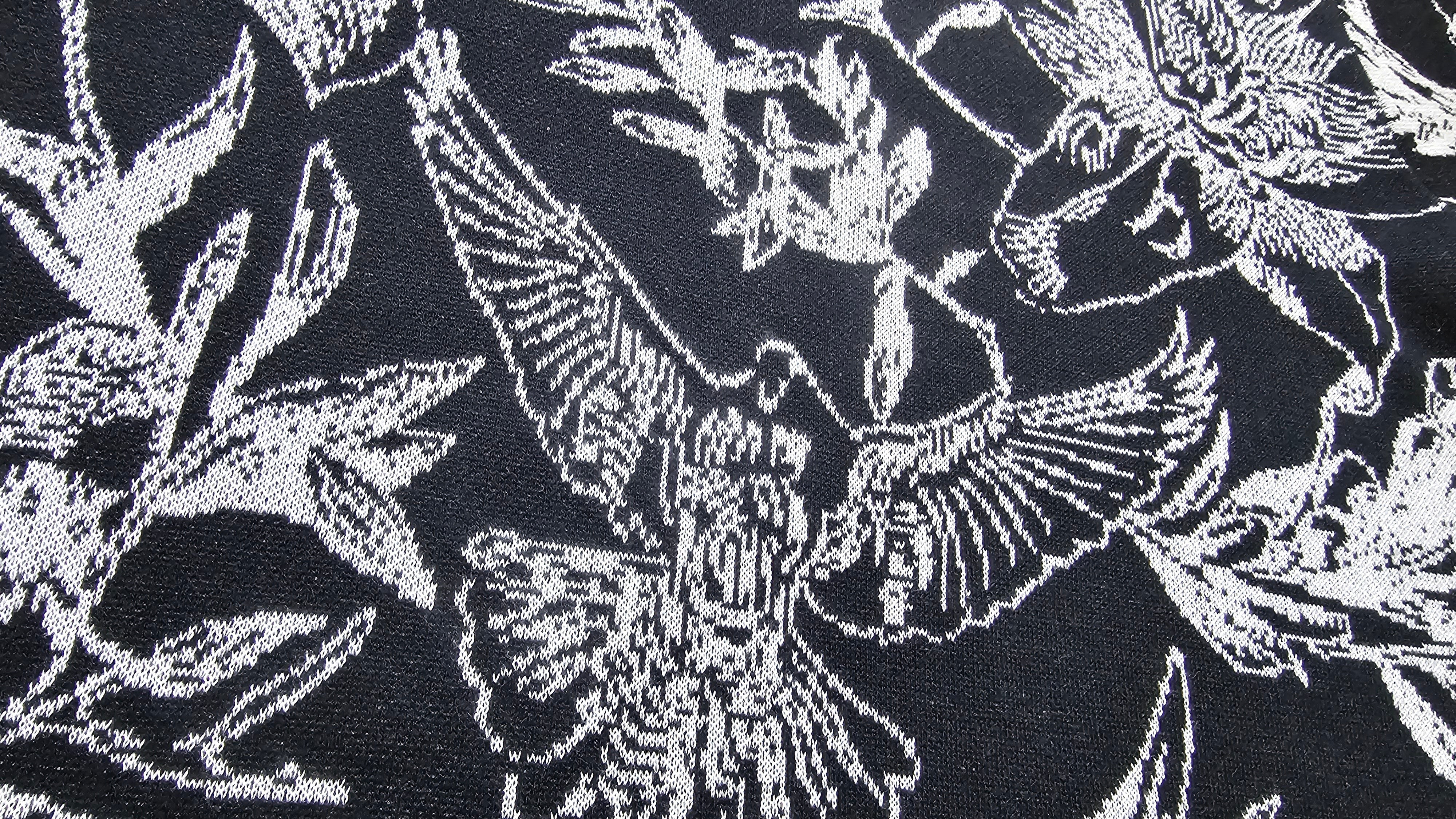 Close-up of a black knitted fabric with white floral and dove pattern