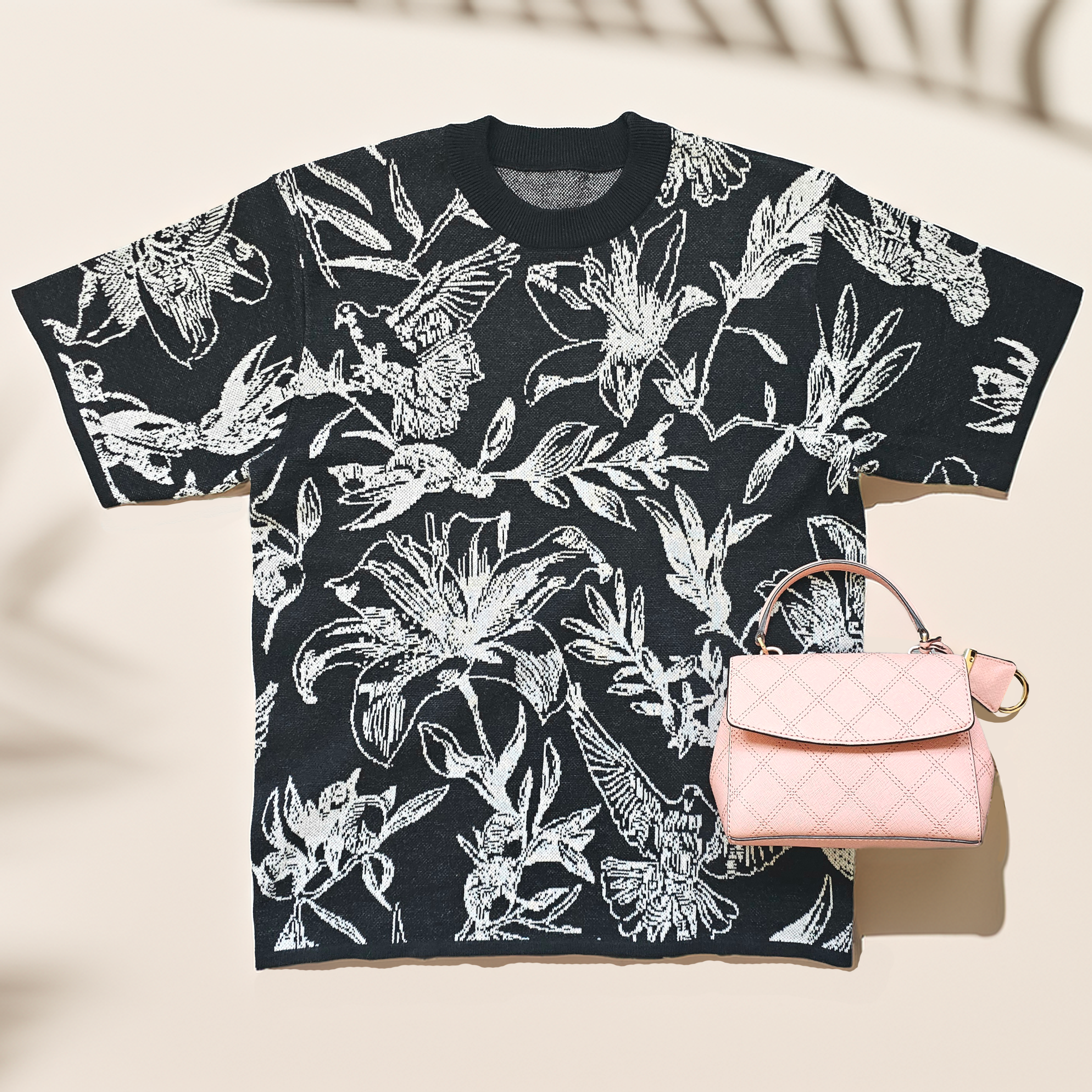 Black t-shirt with white dove and floral pattern with pink handbag on a beige background