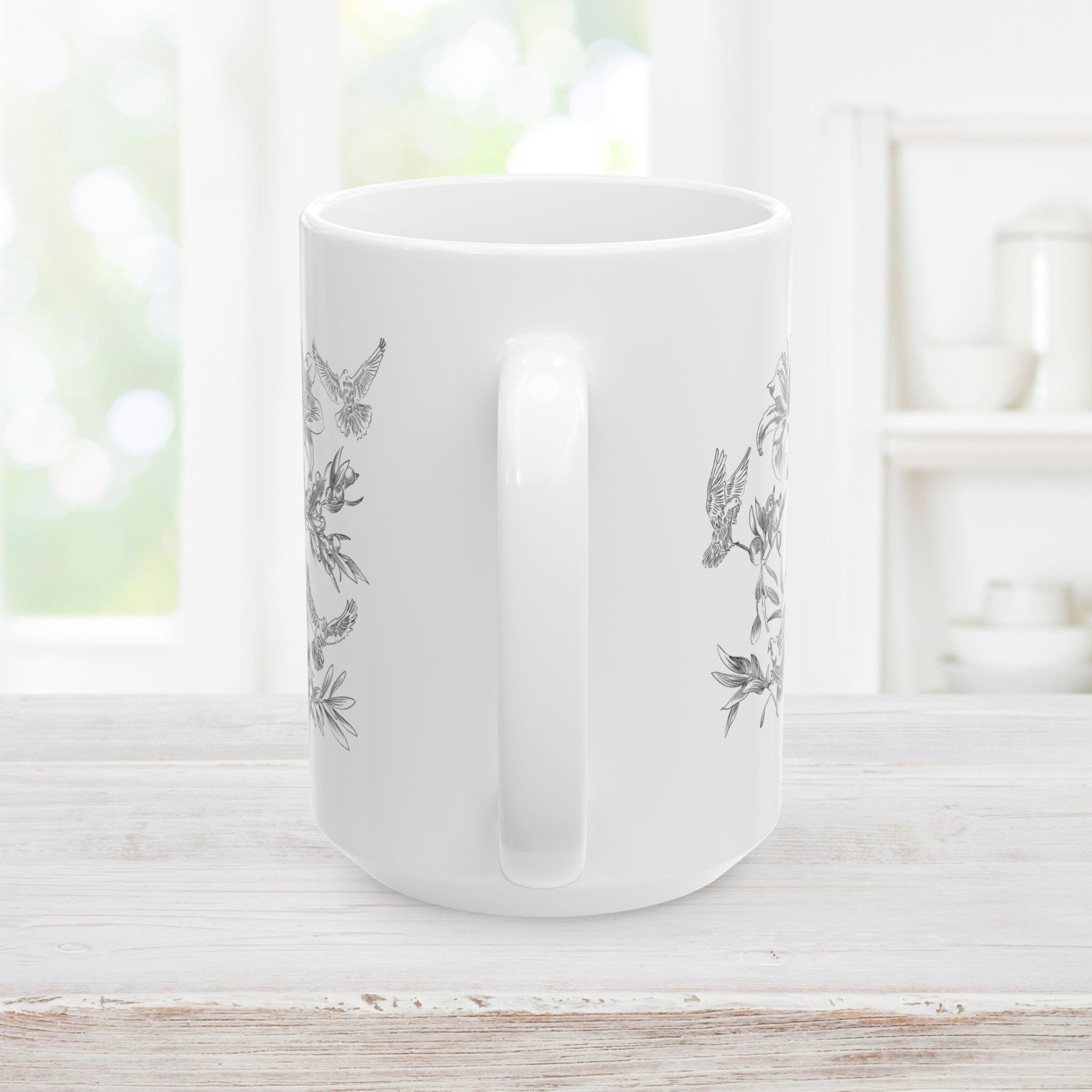 Back side and handle of white mug with floral and dove design on a wooden surface.