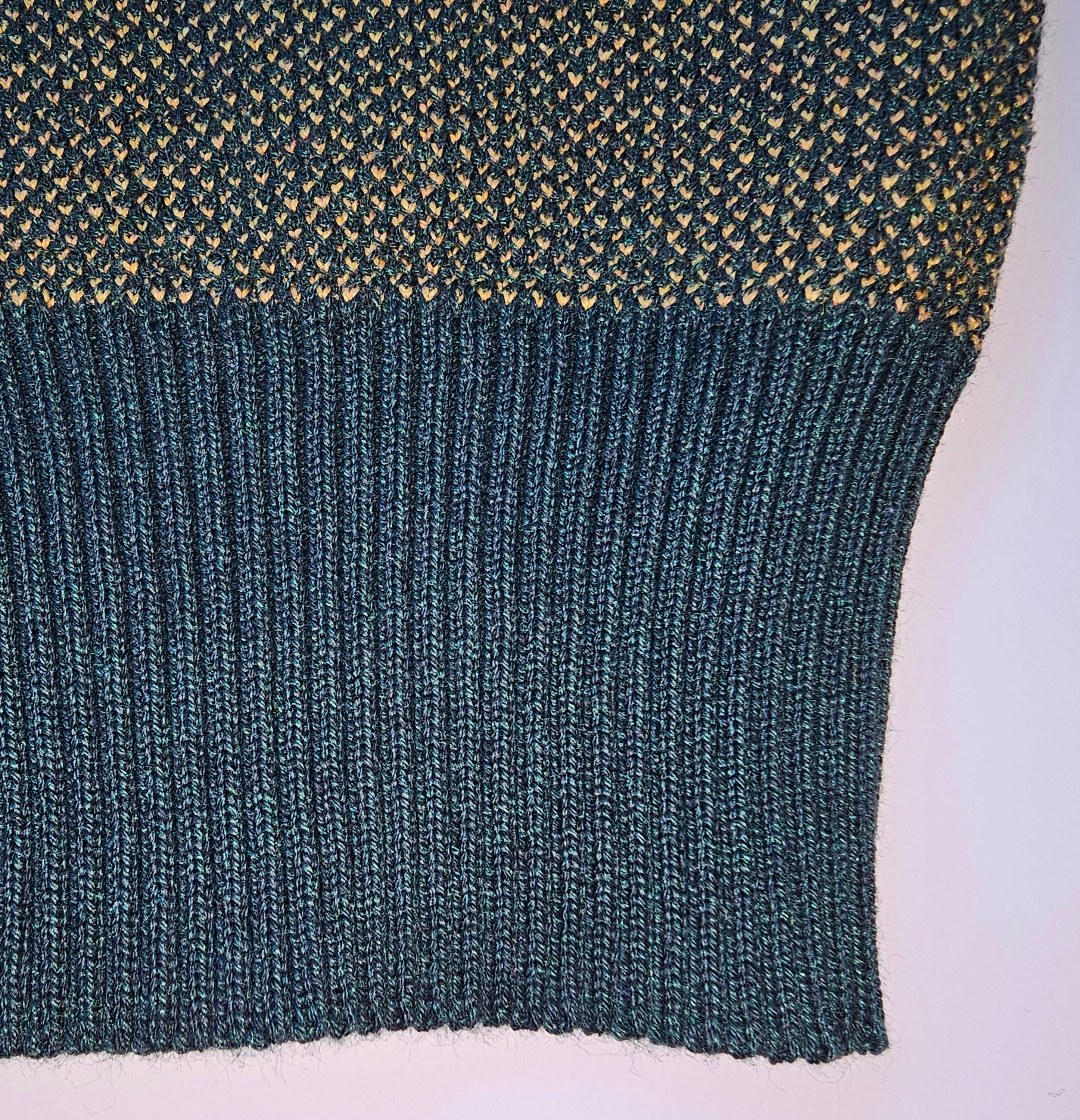 A close-up of the inner rib-knit cuff of the forest green sweater, displaying an incorporated, not cut, ribbed knit cuff.