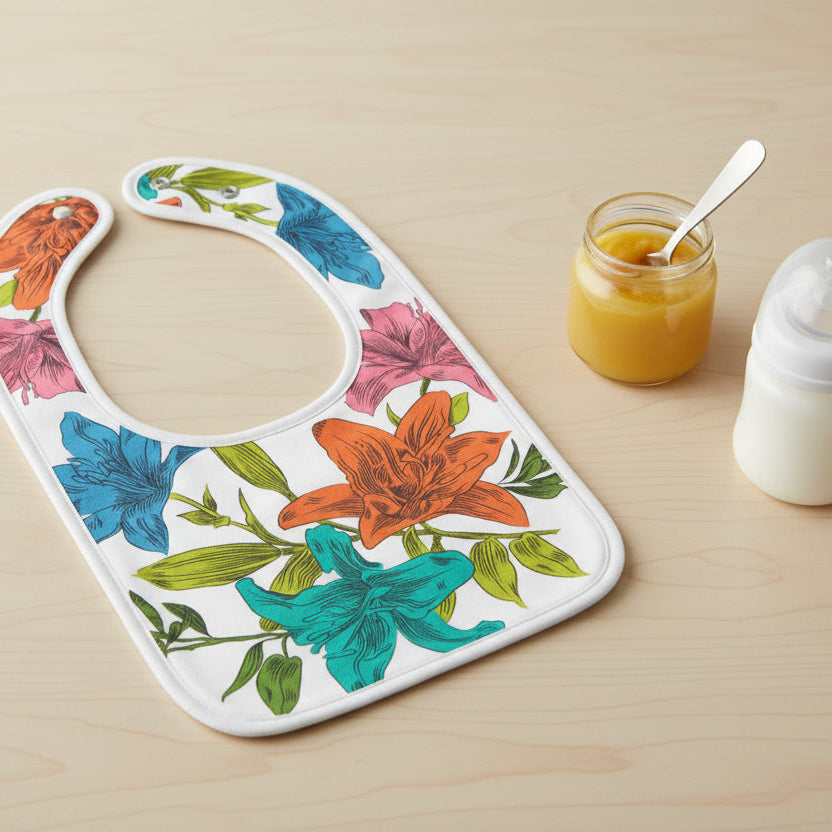 Floral-patterned bib on a wood table next to a jar of baby food and a baby bottle