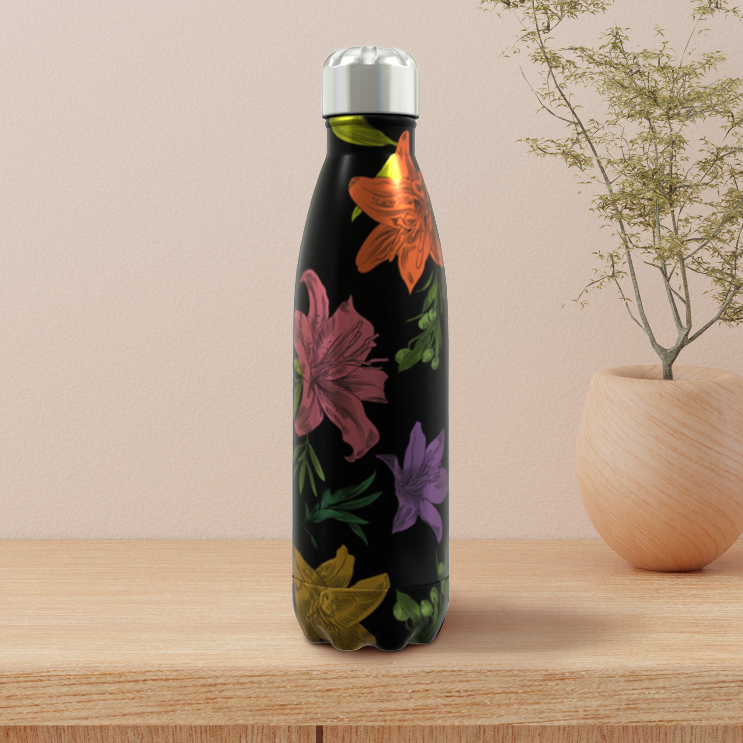 Black water bottle with colorful floral design on a wooden surface with a beige background