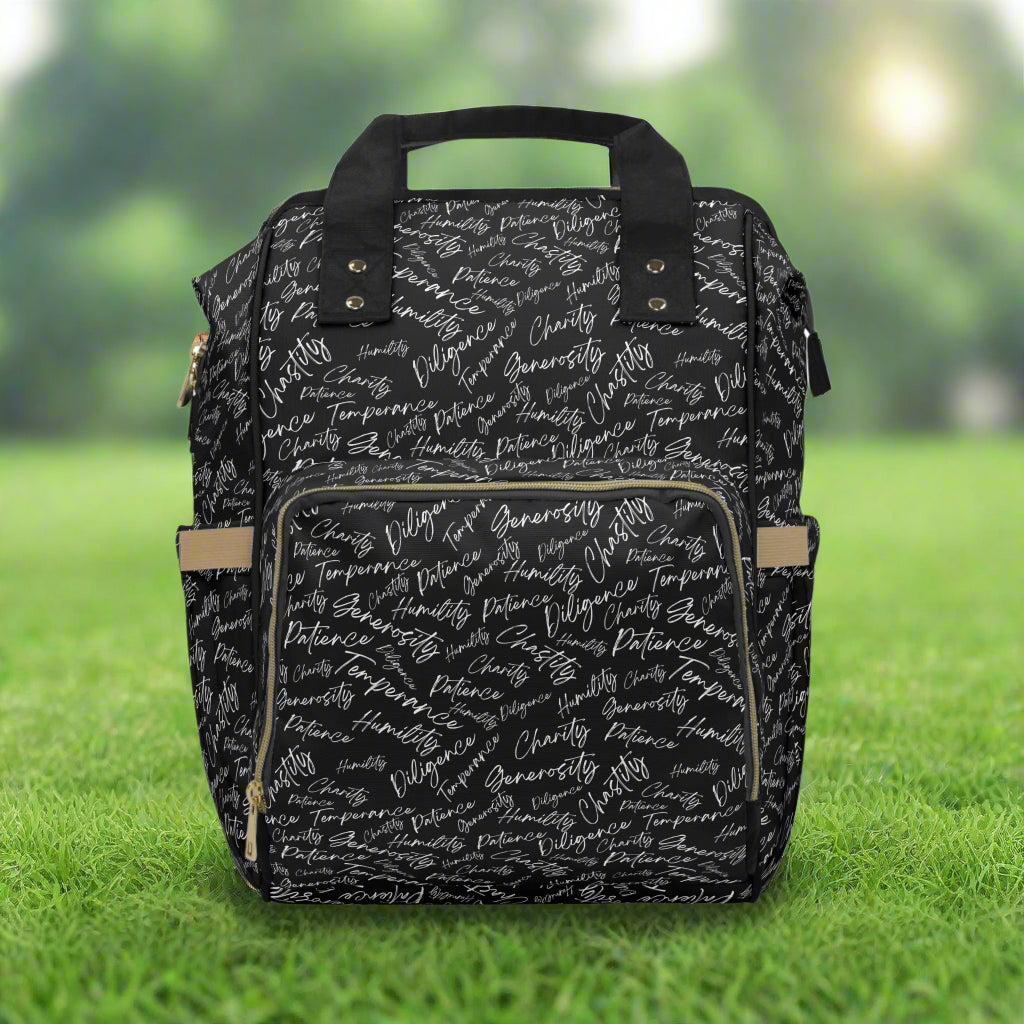 Backpack with adjustable straps with black and white scripted pattern standing on grass in a park
