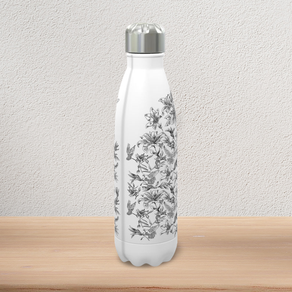 A white, stainless steel water bottle with stainless steel screw cap stands on a pine-wood console. It displays the semi-profile view of a black and white floral and dove pattern, revealing a grayish paint seam along the vertical edge that separates the front image from the back image.