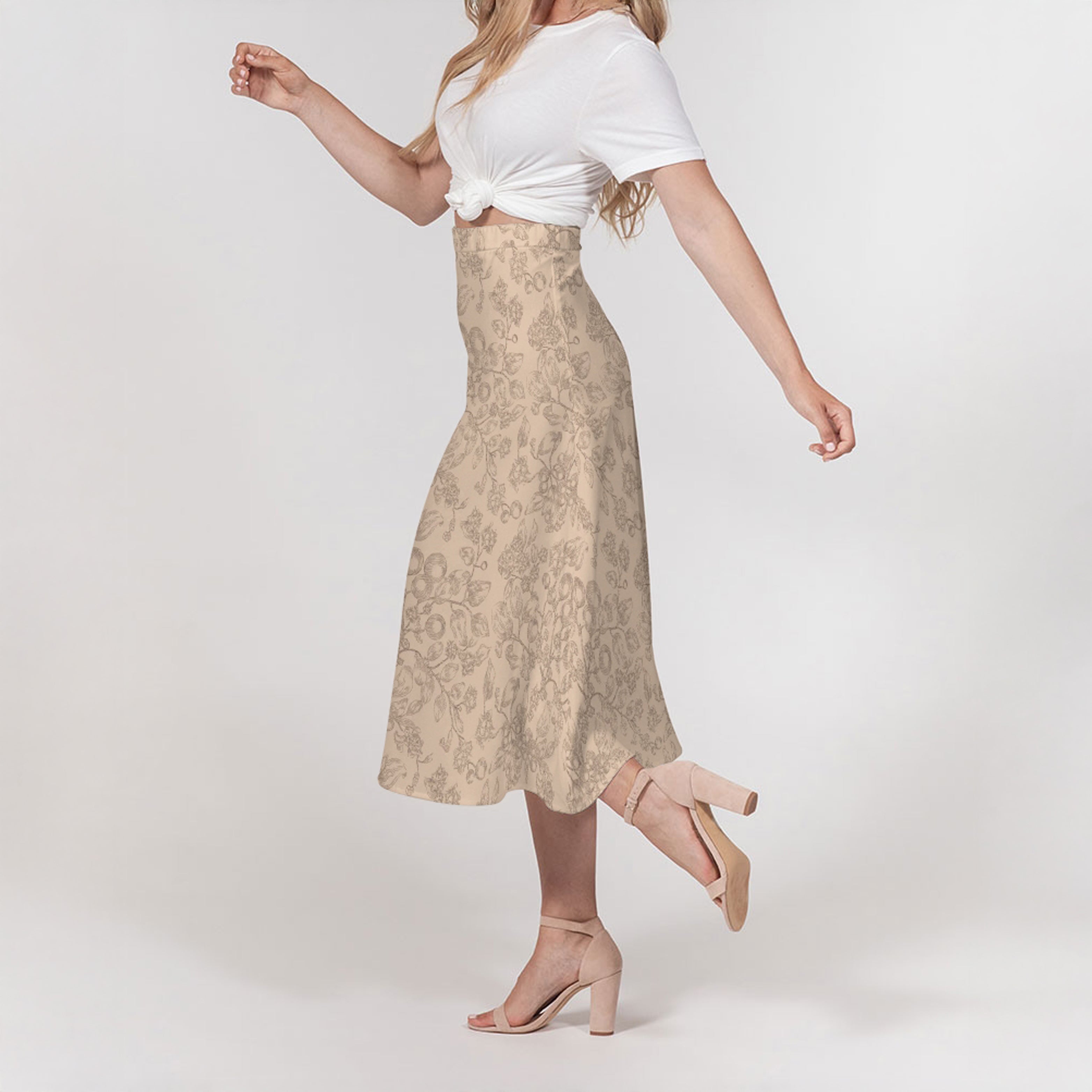 Woman wearing a beige floral skirt and white top on a plain background