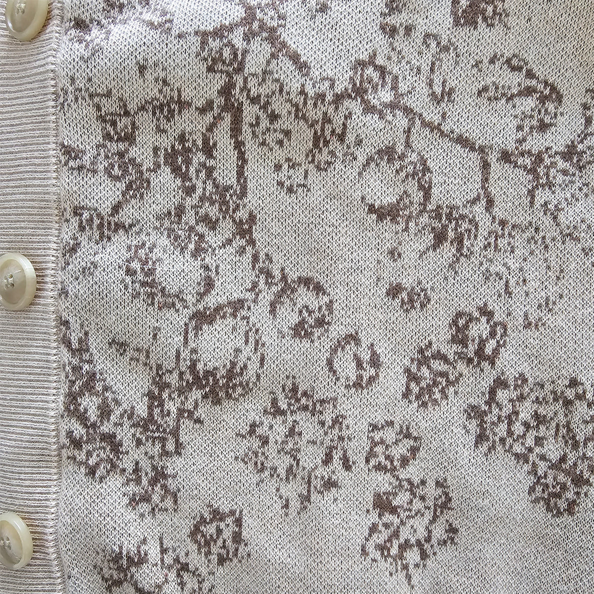 A close up of the brown floral pattern knitted into the beige sweater.