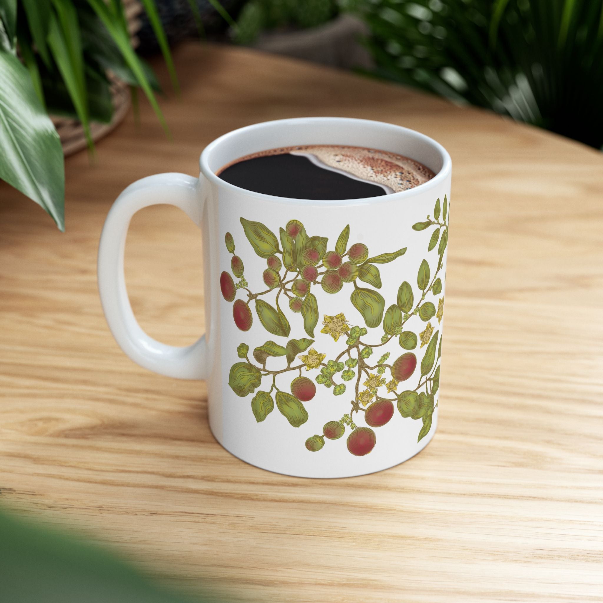 White mug with floral and berry leaf design on a wooden table.