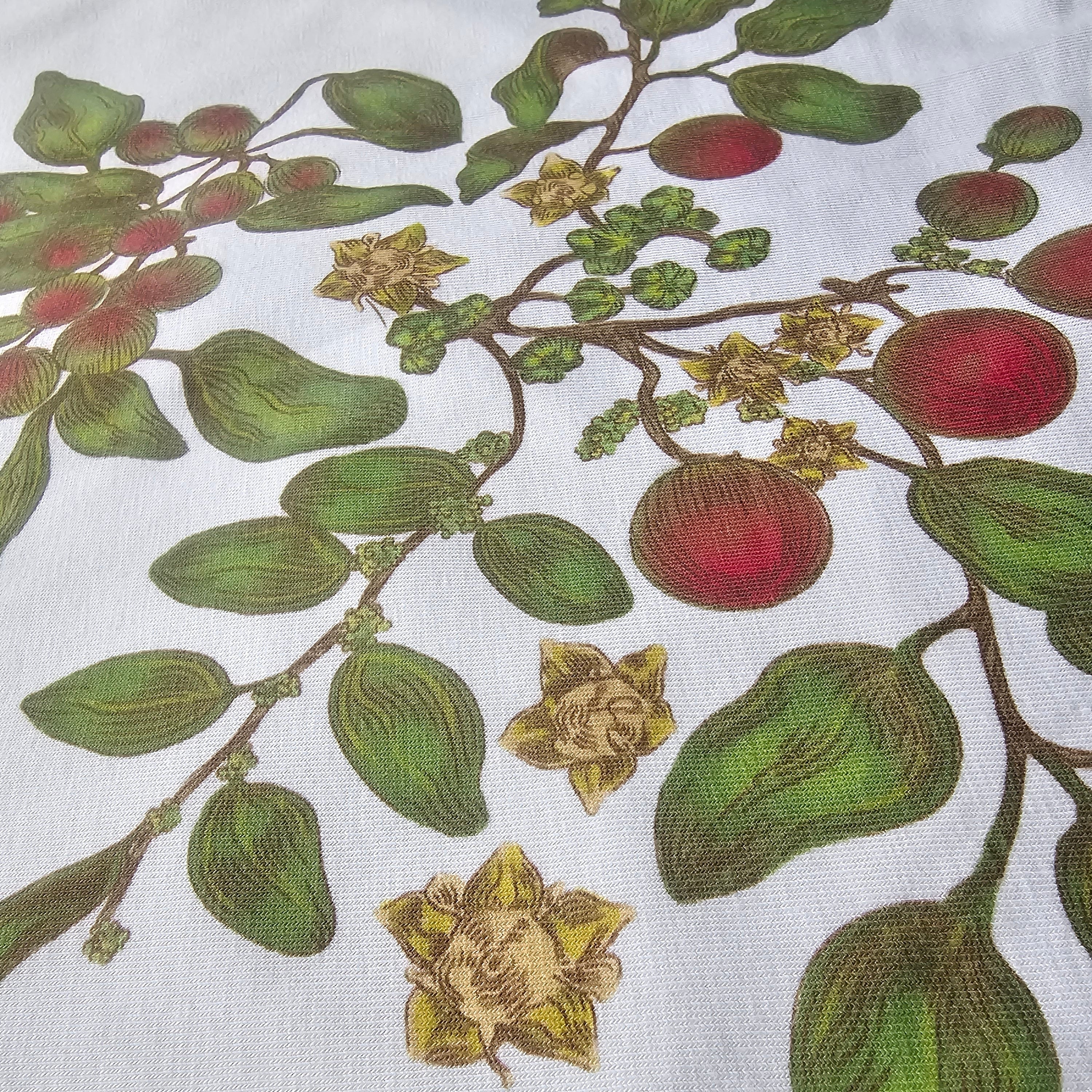 Close-up of a fabric with a detailed botanical pattern featuring leaves and berries on a white background.