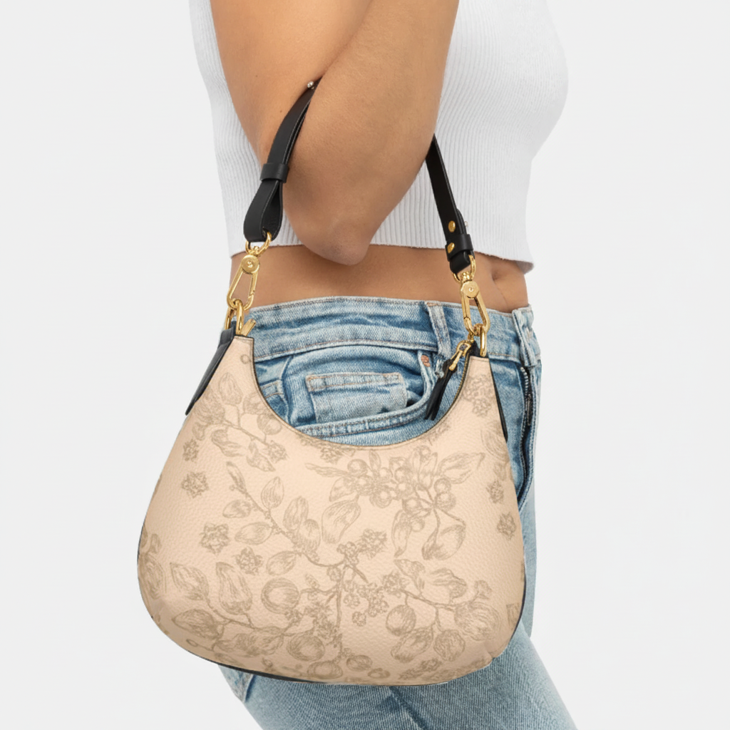 A woman wearing a white top and blue jeans is carrying a beige leather handbag with a floral pattern and gold metal accents. Christian handbag.