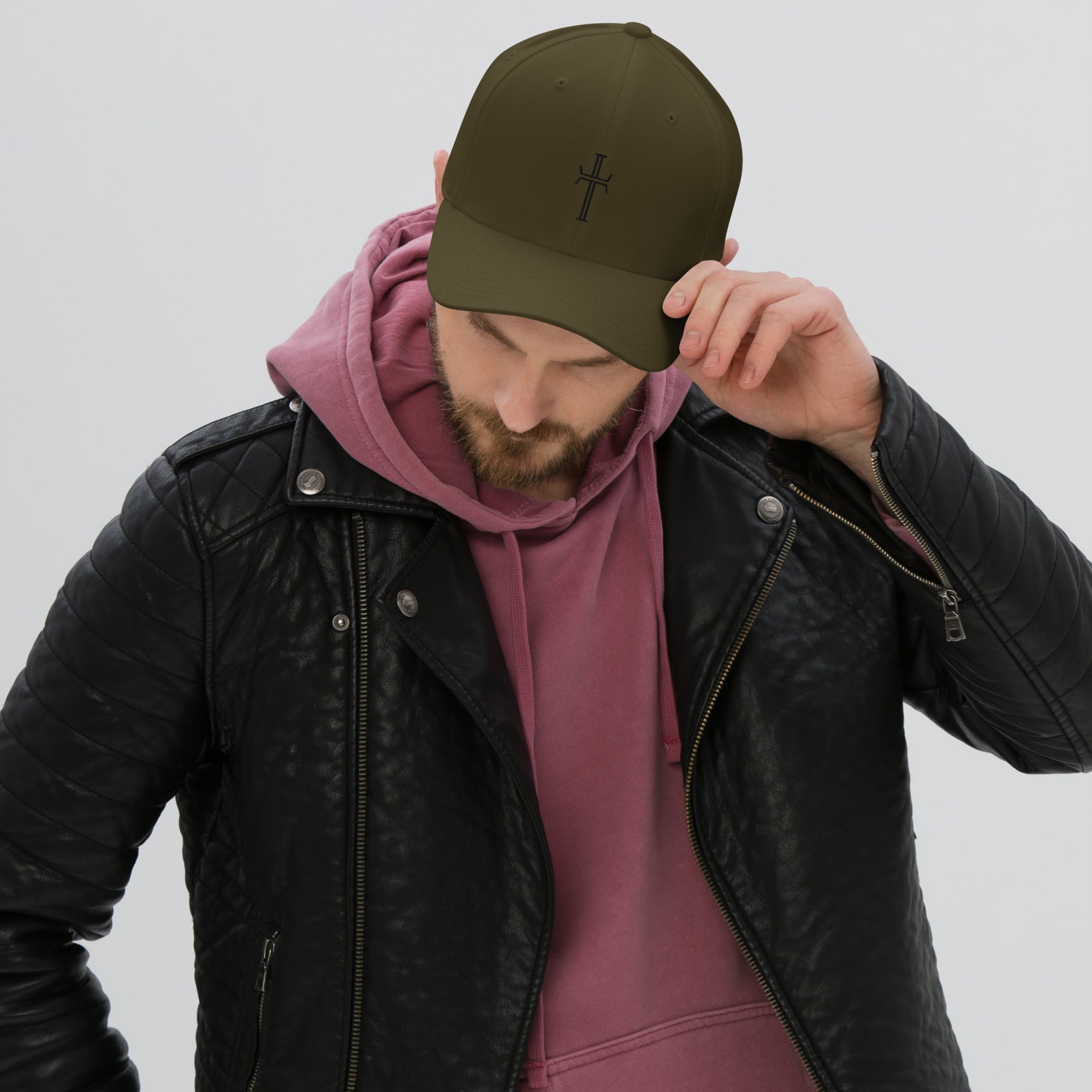 Front view of male model wearing a hoodie and leather jacket, with an olive green, 6-panel, twill baseball cap on his head. The center of the cap has the Purpose cross logo in black embroidery.